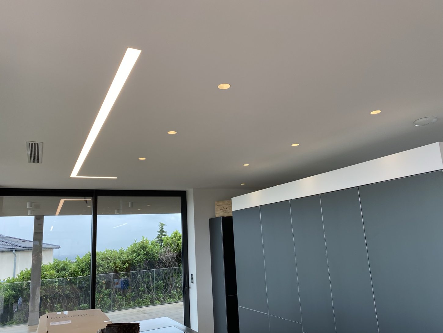 Ligne lumineuse LED en L et spots encastrés dans un intérieur contemporain